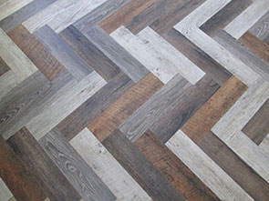 Luxury vinyl planks of various colors arranged in a herringbone pattern make for a stylish, waterproof flooring option for modern homes.