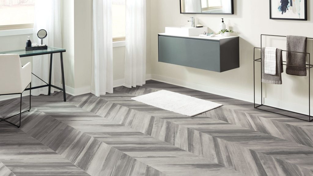 Armstrong Flooring’s CushionStep Forest Luxury Vinyl Planks arranged in a chevron pattern are cushioned and warm underfoot making them a great flooring option for this modern bathroom. 