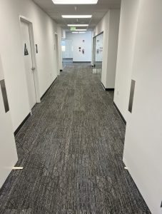 A hallway in an office building with brand new gray carpeting installed by Slaughterbeck Floors.
