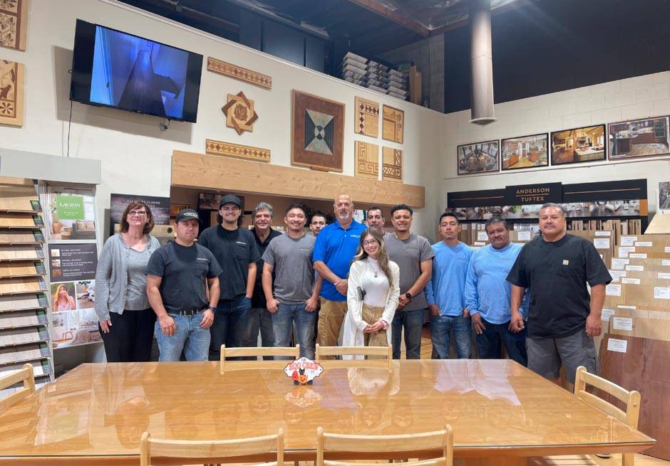 Interior view of Slaughterbeck Floors showroom with team gathered among hardwood flooring samples. 